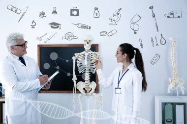 Tıp öğrencisi ve profesör sınıfta insan iskeleti anatomisi okuyor.