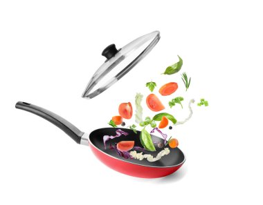 Farklı sebzeler beyaz arka planda tavaya düşüyorlar. Yemek pişirme süreci