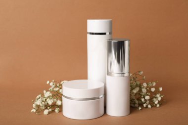 Kahverengi arka planda lüks kozmetik ürünleri ve çiçekler.