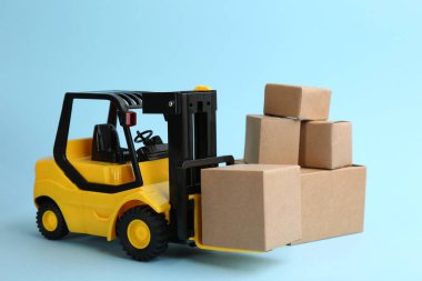 Forklift modeli ve açık mavi arka planda karton kutular. Kurye servisi
