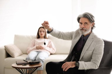 Ofiste hipnoterapi seansı sırasında sarkacı kullanan psikoterapist.