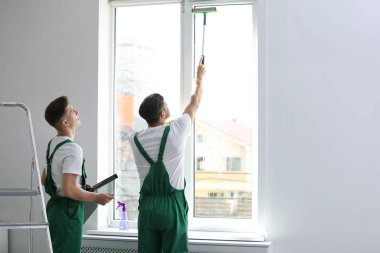 Profesyonel işçiler içeride folyoyla pencereyi boyuyor. Metin için boşluk