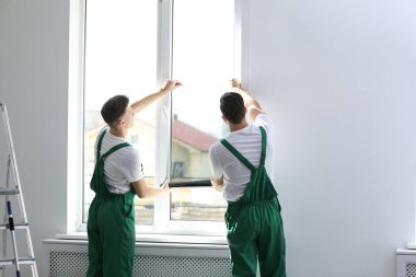 Profesyonel işçiler pencereyi folyoyla boyuyor.