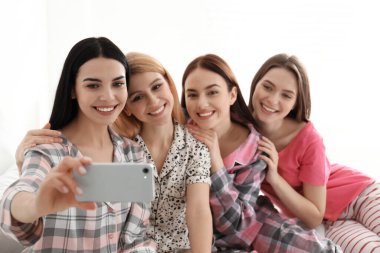 Güzel genç bayanlar şımarık bir partide yatakta selfie çekiyorlar. Kadınlar Günü