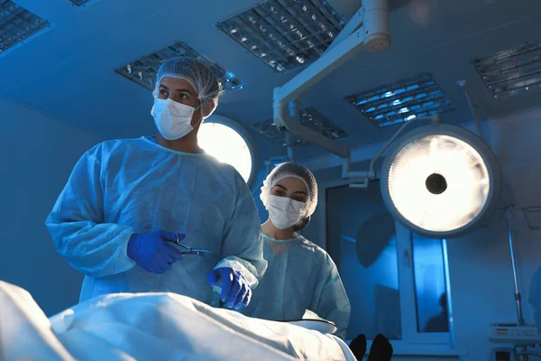 Team of professional doctors performing operation in surgery room