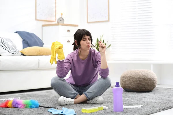 Lazy woman procrastinating while cleaning at home