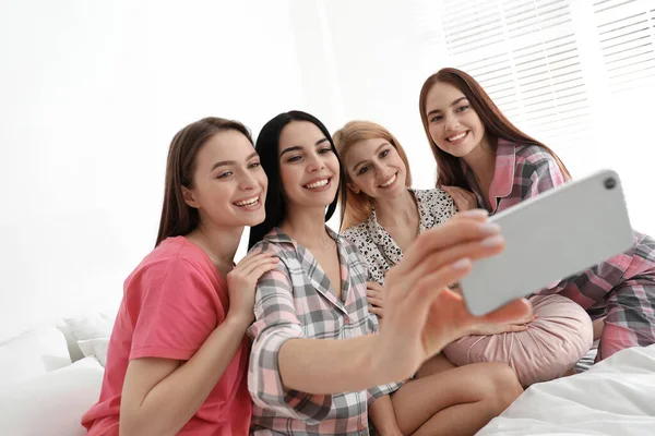 Güzel genç bayanlar şımarık bir partide yatakta selfie çekiyorlar. Kadınlar Günü
