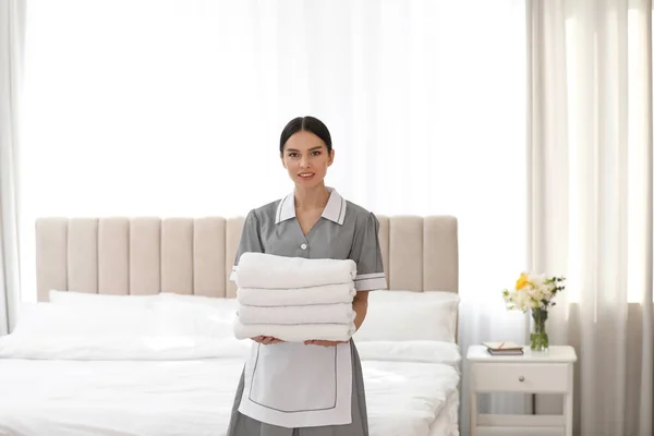 年轻的女服务员在卧室里抱着一堆新鲜的毛巾 — 图库照片