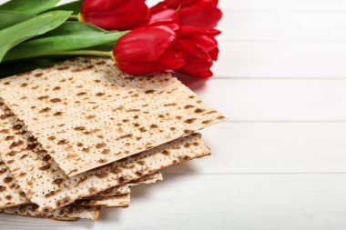 Geleneksel Pesach (Hamursuz Bayramı yemeği) matzası ve beyaz ahşap masada laleler. Metin için boşluk