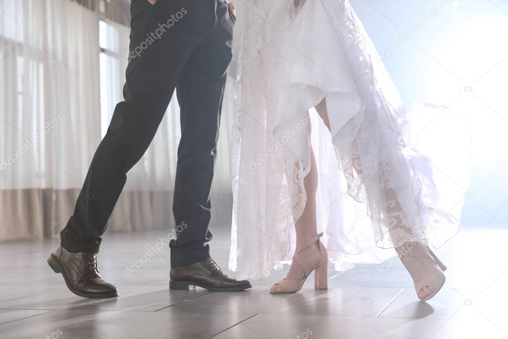 Newlywed couple dancing together in festive hall, closeup of legs