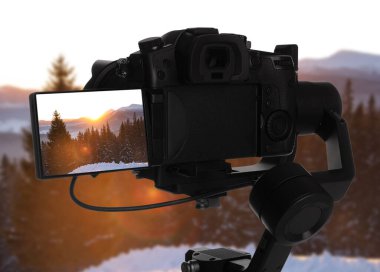 Profesyonel video kamerayla karlı ormanın güzel manzarasını kaydediyorum.