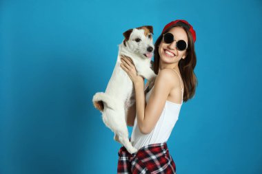 Açık mavi arka planda sevimli Jack Russell Terrier 'ı olan genç bir kadın. Sevimli hayvan