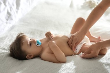 Anne evde bebeğin bezini değiştiriyor.