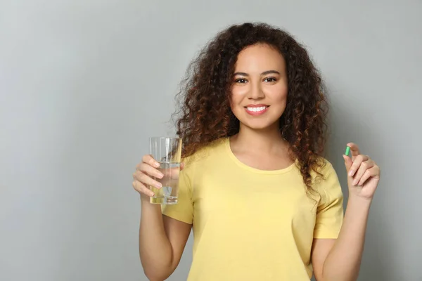Mujer Afroamericana Con Vaso Agua Cápsula Vitamínica Sobre Fondo Gris — Foto de Stock