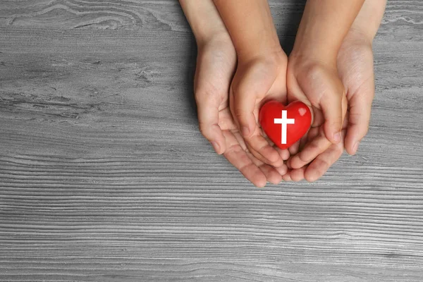 Woman Child Holding Heart Cross Symbol Grey Wooden Background Top — Stock Photo, Image