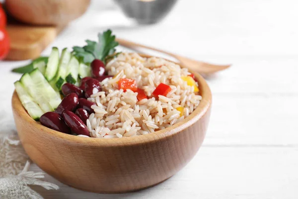 Delicious rice with beans served on white wooden table, closeup