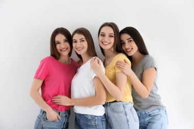 Kot pantolonlu güzel genç bayanlar ve beyaz arka planda renkli tişörtler. Kadın Günü