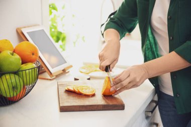 Mutfaktaki masada tabletli bir kadın yemek pişiriyor.
