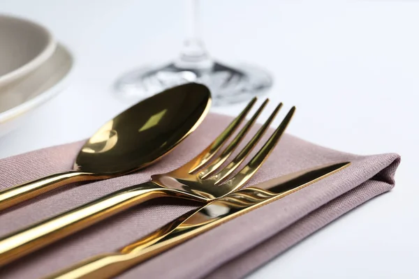 Stylish elegant cutlery set with napkin on white table, closeup