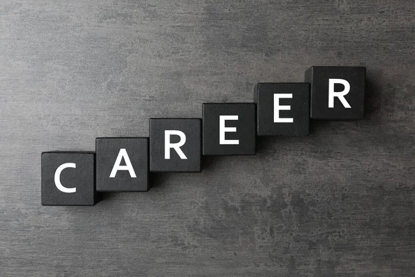 Cubes with word CAREER on grey stone background, flat lay