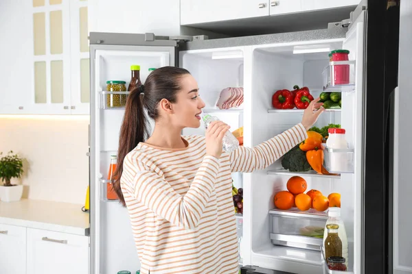 Mujer Joven Bebiendo Agua Cerca Refrigerador Abierto Cocina — Foto de Stock