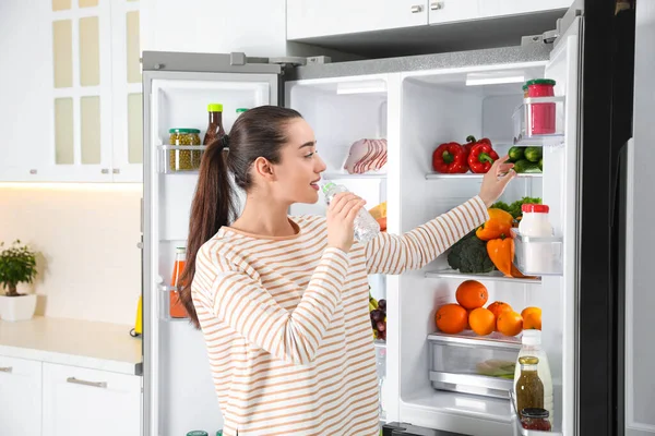 Jonge Vrouw Drinkwater Buurt Van Open Koelkast Keuken — Stockfoto