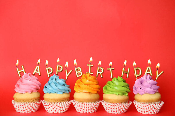 Birthday cupcakes with burning candles on red background. Space for text