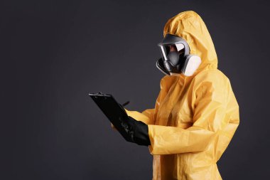 Kimyasal koruyucu giysili kadın gri arka planda pano tutuyor, mesaj için yer var. Virüs araştırması
