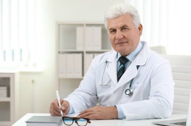 İş yerinde beyaz önlüklü kıdemli doktorun portresi.
