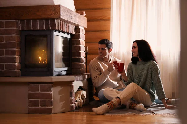 可爱的夫妇与美味的可可靠近壁炉在地板上的家 — 图库照片