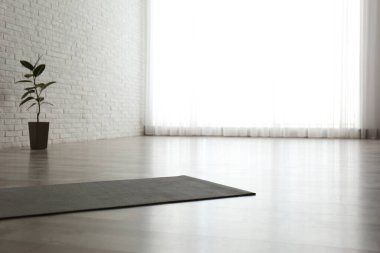 Odada yerde yuvarlanmış gri yoga minderi var. Metin için boşluk