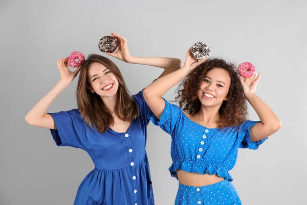 Hermosas Mujeres Jóvenes Con Rosquillas Sobre Fondo Gris Claro — Foto de Stock