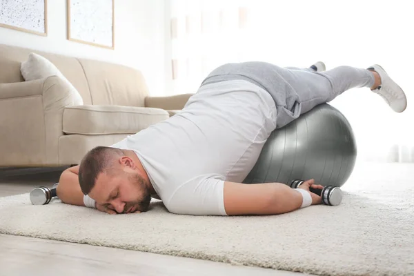 睡懒觉的超重男子 带着运动器材睡在家里的地板上 — 图库照片