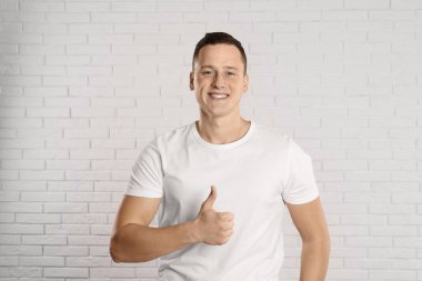 Beyaz tuğla duvarın yanındaki yakışıklı genç adam.