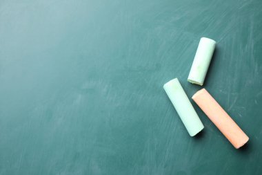 Renkli tebeşir parçaları yeşil tahtada, düz yerde. Metin için boşluk