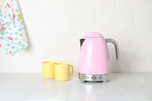 厨房柜台上的现代电水壶和杯子 — 图库照片