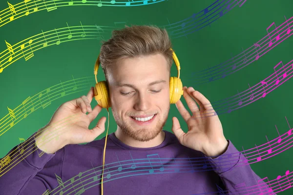 Przystojny Młodzieniec Słuchający Muzyki Słuchawkami Zielonym Tle — Zdjęcie stockowe