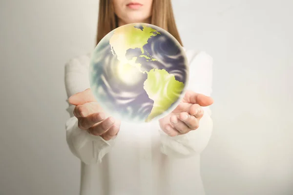 Woman holding Earth on light background, closeup