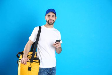 Termal çantalı kurye ve açık mavi arka planda cep telefonu, mesaj için yer var. Yemek dağıtım servisi.