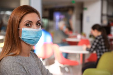Kafedeki tıbbi maskeli kadın. Virüs koruması