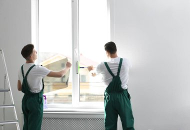 Profesyonel işçiler pencereyi folyoyla boyuyor.