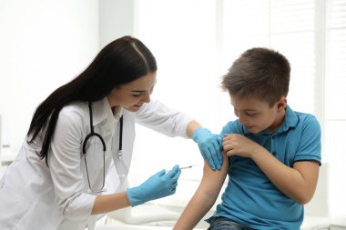 Modern klinikte küçük bir çocuğu aşılayan doktor.