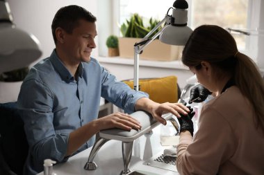 Profesyonel manikürcü müşterisiyle güzellik salonunda çalışıyor.