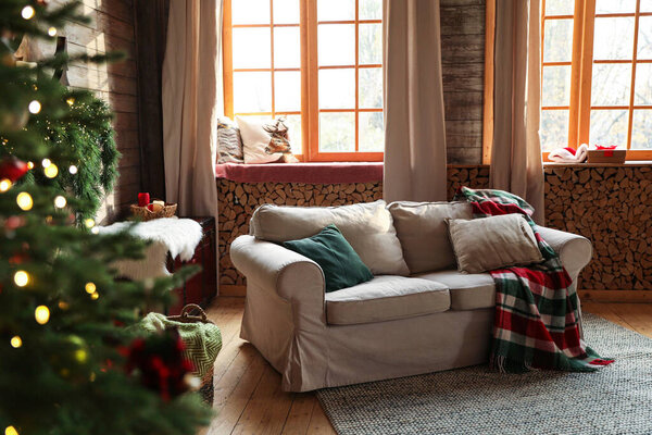 Festive interior with comfortable sofa and decorated Christmas tree