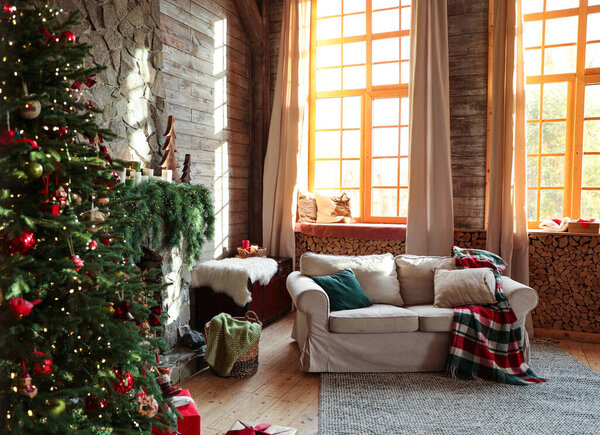 Festive interior with comfortable sofa and decorated Christmas tree