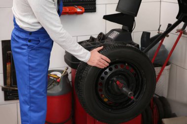 Lastik servisinde tekerlek dengeleme makinesiyle çalışan tamirci, yakın çekim