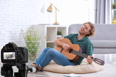 Müzik öğretmeni evde gitar dersi kaydediyor.