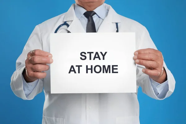 Arzt Hält Schild Mit Text Stay Home Auf Blauem Hintergrund — Stockfoto