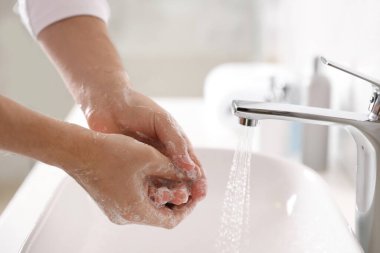 Adam ellerini sabunla yıkıyor lavabonun üzerinde, yakın plan.