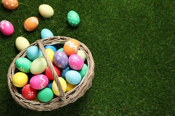 五彩缤纷的复活节彩蛋在绿草的篮子里 俯瞰上方 案文的篇幅 — 图库照片